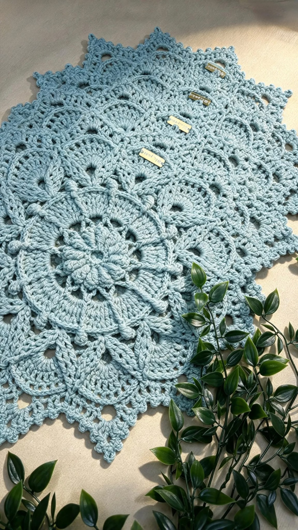Toalha de renda em crochê azul-claro com ramos de folhagem
