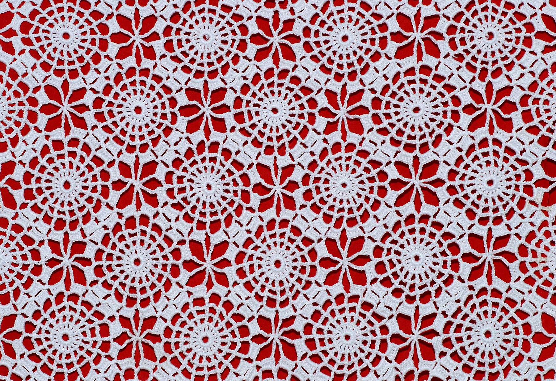 Toalha de renda em crochê branco sobre fundo vermelho